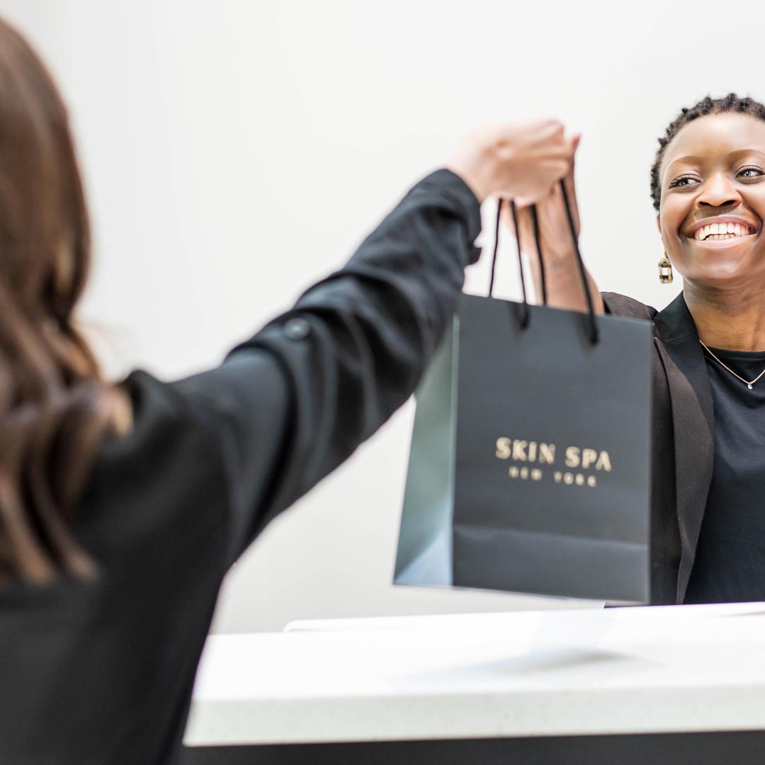 Skin Spa Employee handing a retail bag